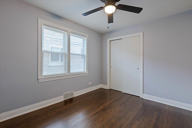 unfurnished bedroom with dark hardwood / wood-style flooring, ceiling fan, and a closet