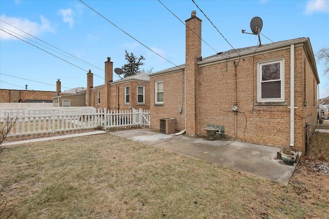 rear view of property with a yard, central air condition unit, and a patio area