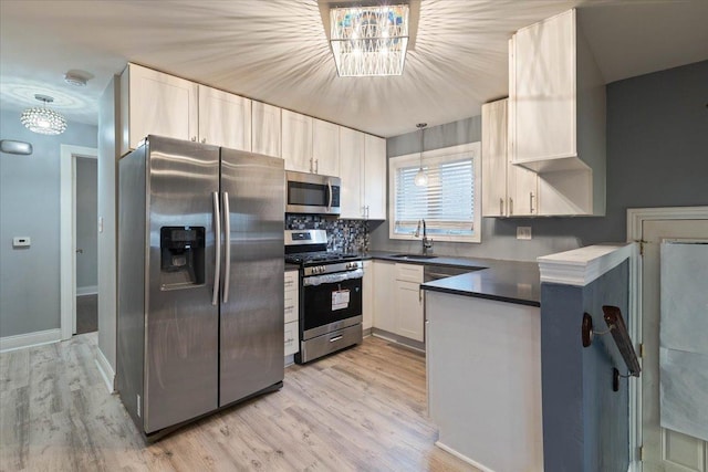 kitchen featuring sink, white cabinetry, light wood-type flooring, pendant lighting, and appliances with stainless steel finishes