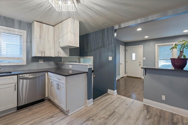 kitchen featuring white cabinets, stainless steel dishwasher, light hardwood / wood-style floors, and sink