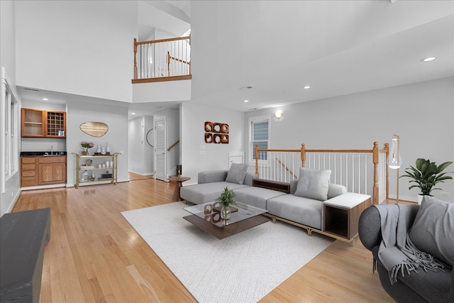 living room featuring a towering ceiling and light hardwood / wood-style floors