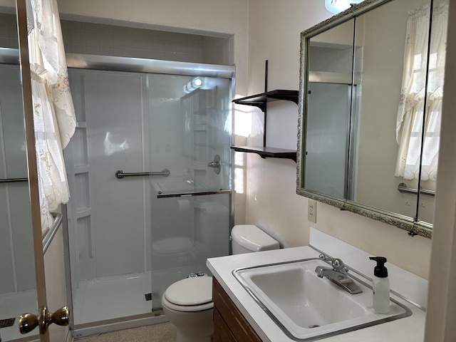 bathroom featuring a shower with door, vanity, and toilet