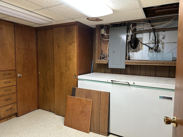 basement with electric panel and a drop ceiling