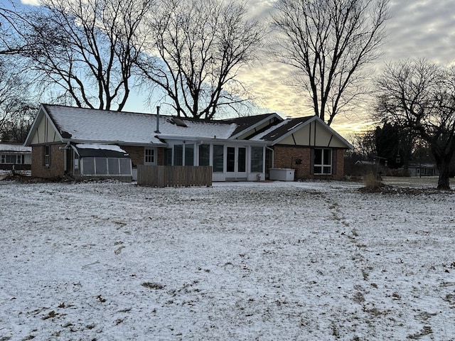 snow covered house featuring a sunroom