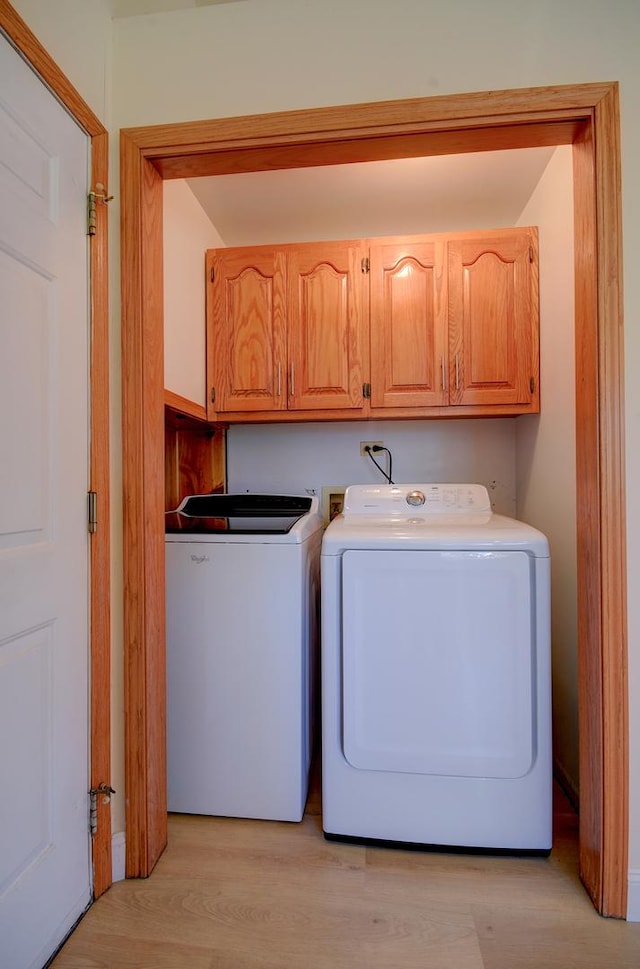 laundry area featuring cabinets, separate washer and dryer, and light wood-type flooring