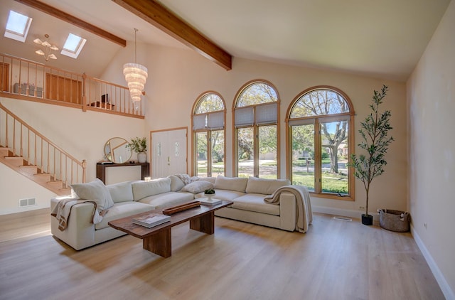 living room featuring a skylight, light hardwood / wood-style flooring, high vaulted ceiling, and beamed ceiling