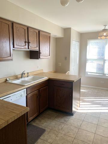 kitchen featuring wood counters, kitchen peninsula, light tile patterned floors, white dishwasher, and sink