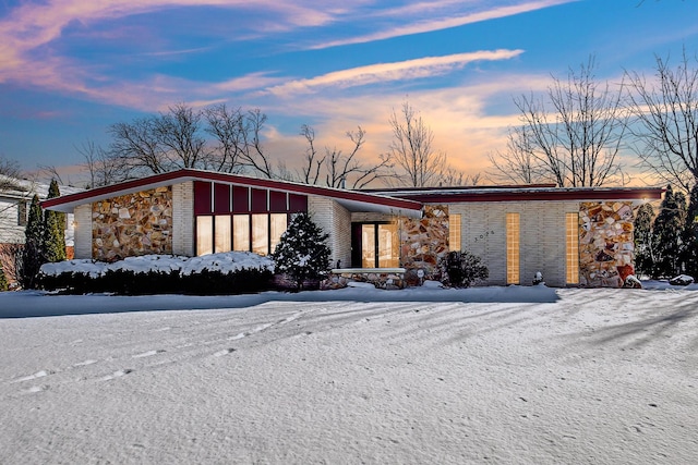 mid-century modern home featuring stone siding and brick siding