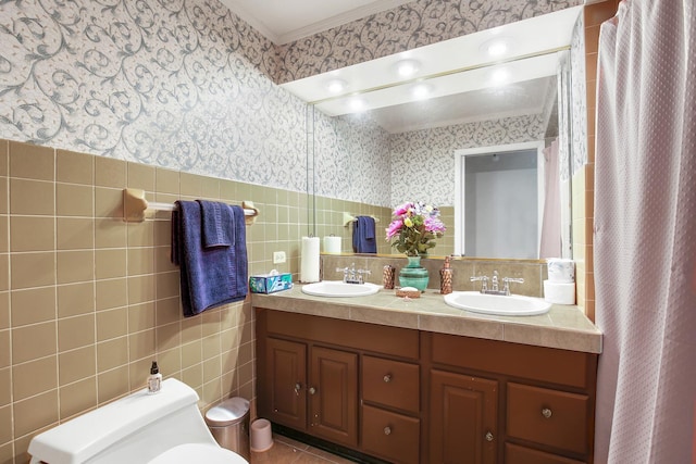 full bath with double vanity, a sink, tile walls, and wallpapered walls