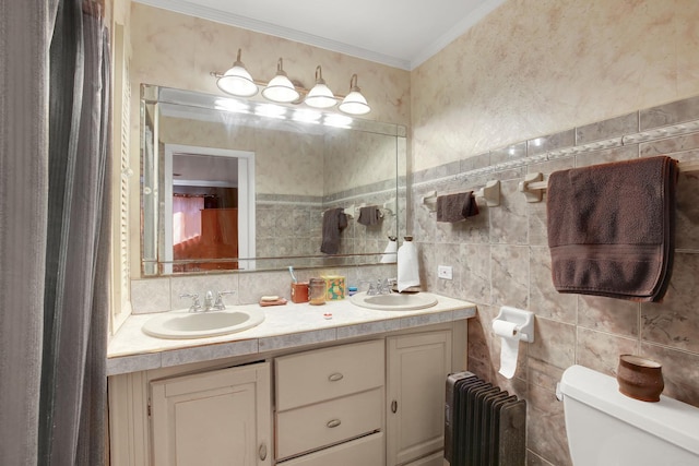 full bath with crown molding, a sink, radiator heating unit, and double vanity