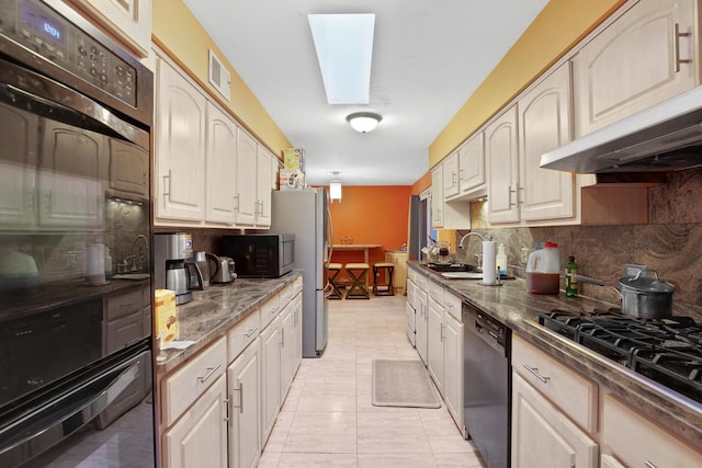 kitchen with black dishwasher, gas stovetop, dark countertops, backsplash, and a sink