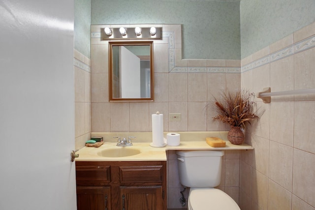 half bath with vanity, toilet, and tile walls