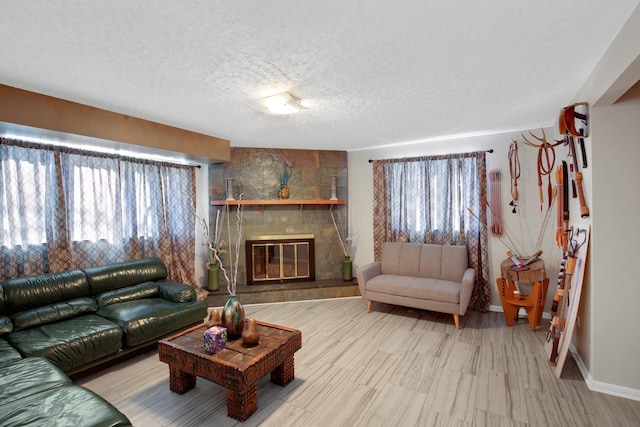 living room featuring a textured ceiling, a stone fireplace, a wealth of natural light, and baseboards