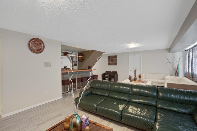 living area featuring baseboards, a textured ceiling, and wood finished floors