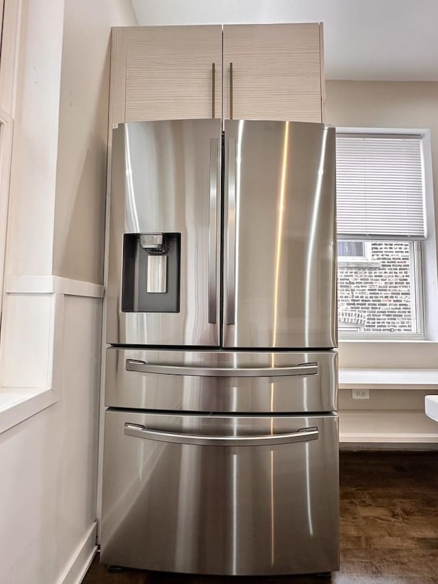 room details with dark wood-type flooring, light brown cabinetry, and stainless steel fridge