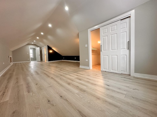 additional living space featuring light wood-type flooring and vaulted ceiling