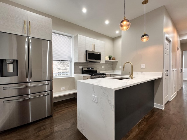 kitchen featuring stainless steel appliances, sink, decorative light fixtures, kitchen peninsula, and backsplash