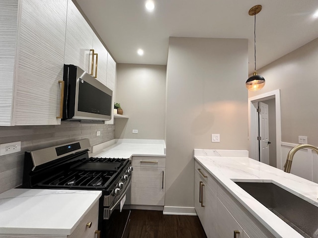 kitchen featuring sink, light stone counters, decorative backsplash, hanging light fixtures, and appliances with stainless steel finishes