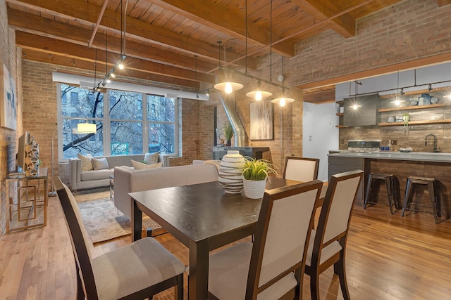 dining area with beamed ceiling, wood ceiling, brick wall, and light hardwood / wood-style flooring