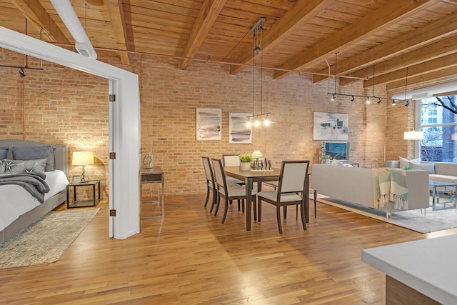 dining space featuring brick wall, hardwood / wood-style floors, a high ceiling, wooden ceiling, and beam ceiling