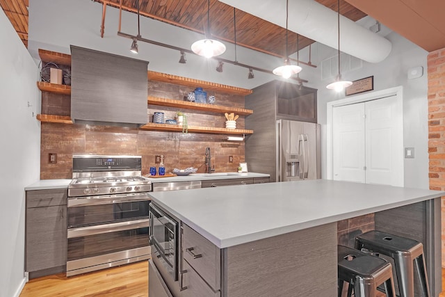 kitchen featuring sink, stainless steel appliances, light hardwood / wood-style floors, a kitchen island, and decorative backsplash