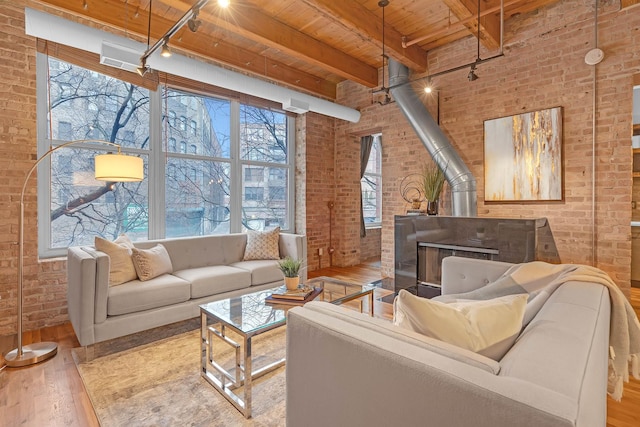 living room featuring a wood stove, wooden ceiling, track lighting, brick wall, and light hardwood / wood-style floors