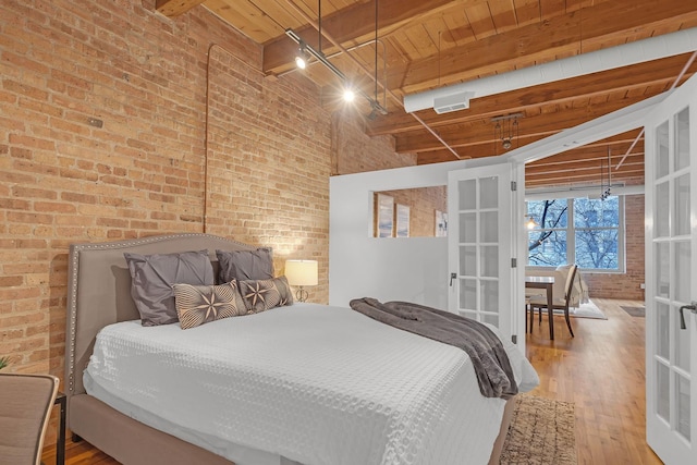 bedroom with wood-type flooring, brick wall, wooden ceiling, and beam ceiling