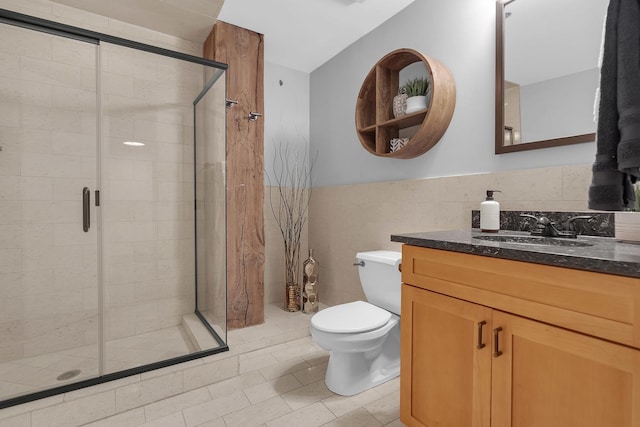 bathroom featuring a shower with door, vanity, tile walls, and toilet