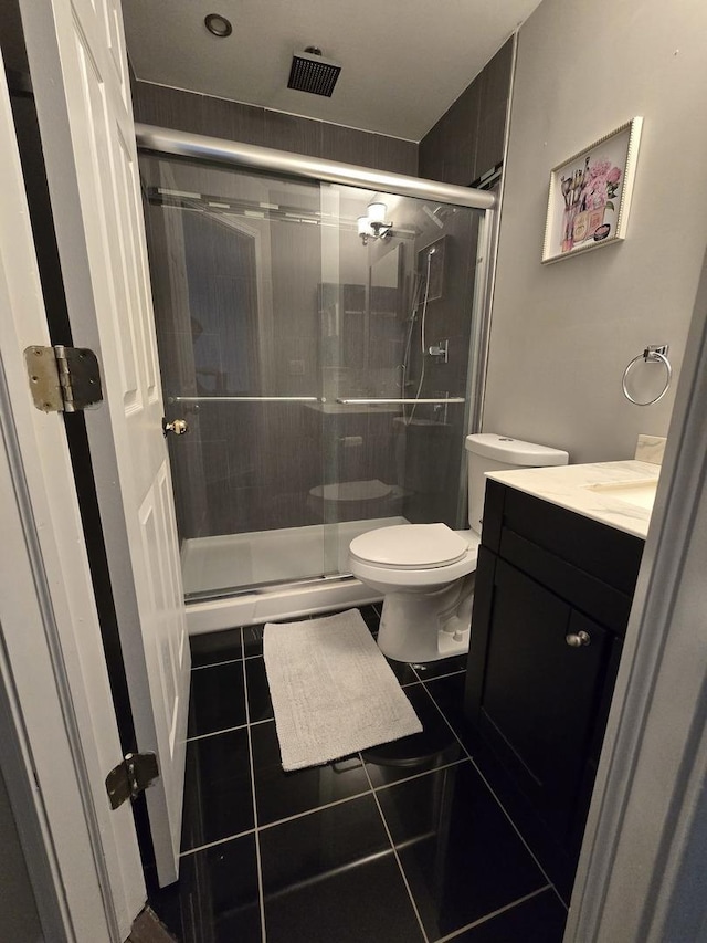 bathroom with a shower with shower door, tile patterned floors, vanity, and toilet