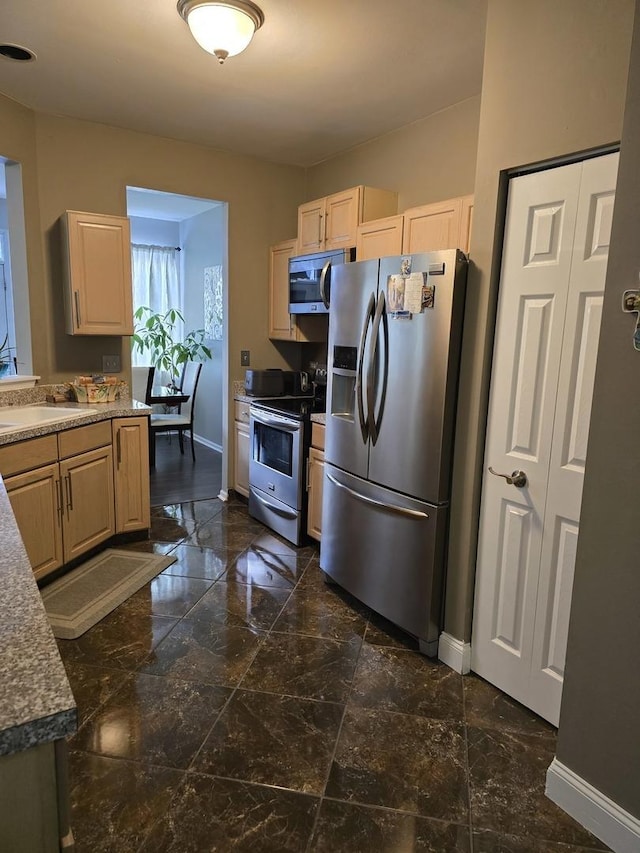 kitchen featuring appliances with stainless steel finishes, light brown cabinetry, and sink