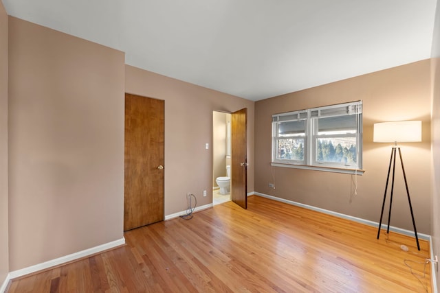 unfurnished bedroom with wood-type flooring and ensuite bath