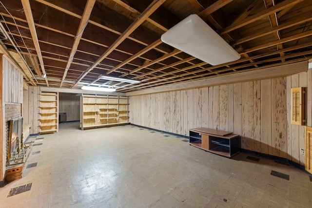 basement featuring wooden walls and a fireplace