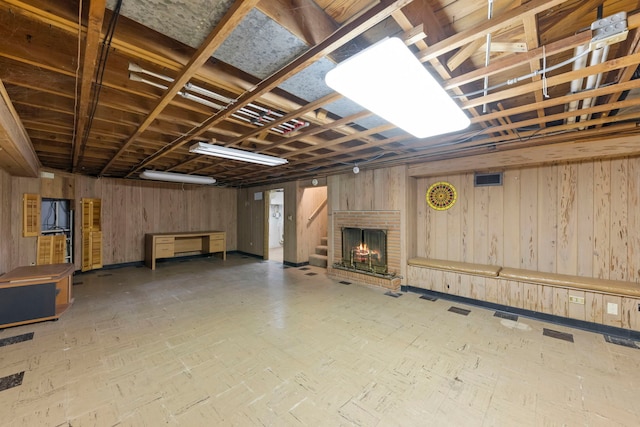 basement featuring wooden walls and a fireplace