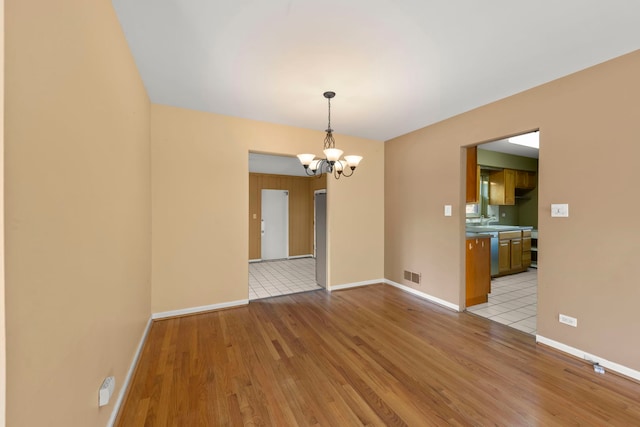 spare room featuring a notable chandelier, light hardwood / wood-style flooring, and sink