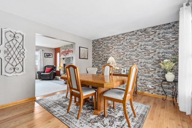 dining space featuring light wood-type flooring and a stone fireplace