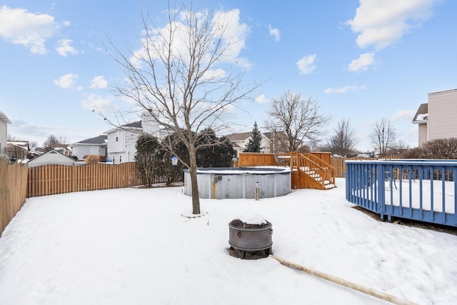 yard covered in snow with a fire pit and a pool side deck