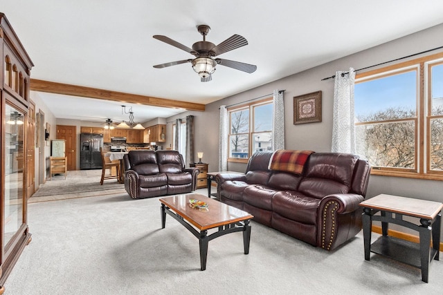 living room with beam ceiling, light colored carpet, and ceiling fan