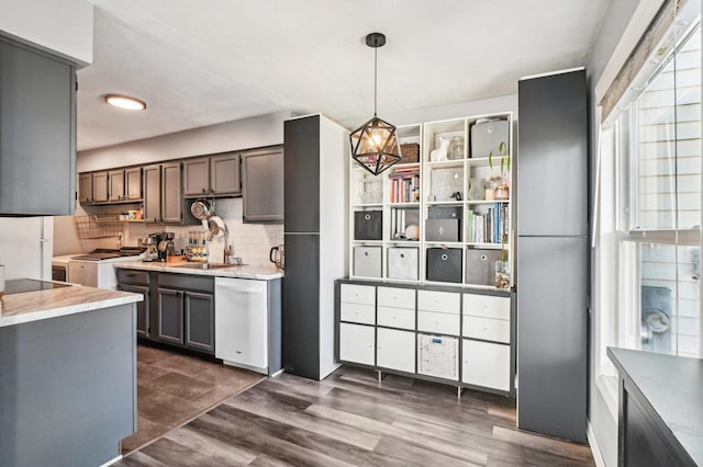 kitchen featuring dark hardwood / wood-style flooring, decorative light fixtures, sink, white appliances, and decorative backsplash