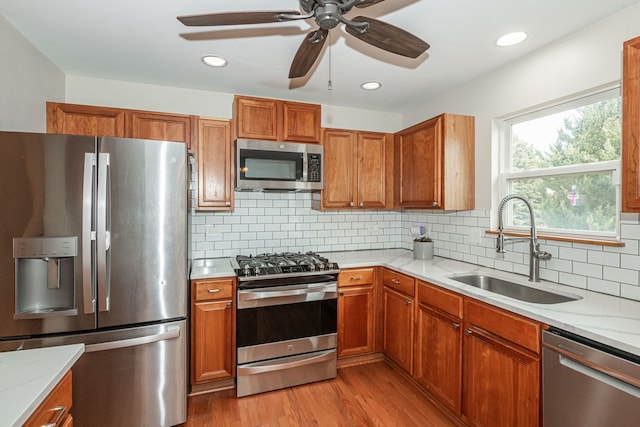 kitchen with sink, decorative backsplash, light hardwood / wood-style floors, stainless steel appliances, and light stone countertops