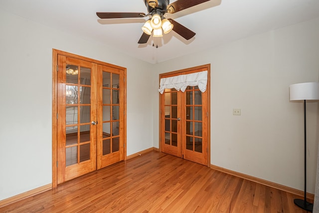 empty room with french doors, ceiling fan, and light wood-type flooring