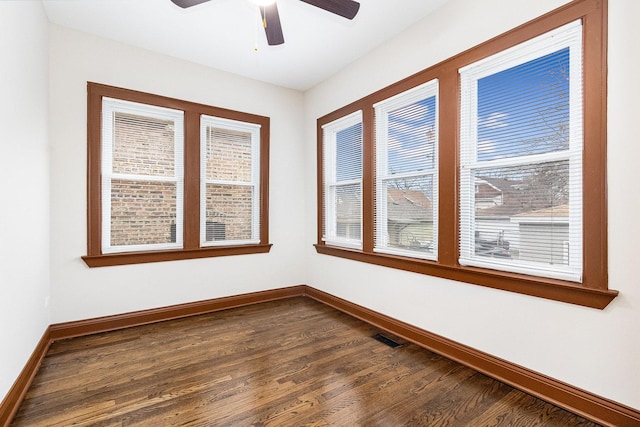 empty room featuring dark wood-type flooring, ceiling fan, and a wealth of natural light