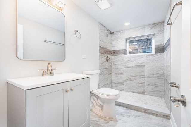 bathroom with toilet, a tile shower, and vanity