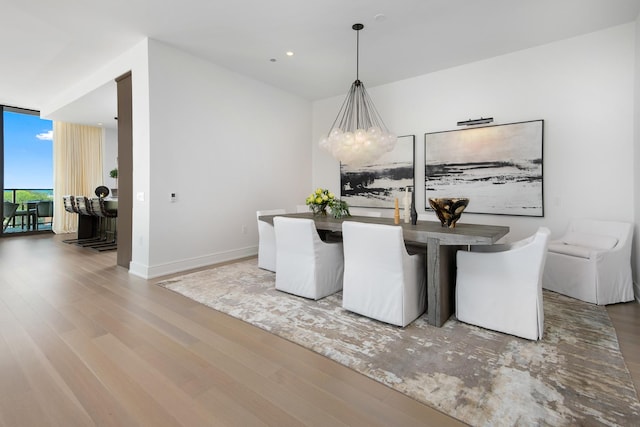 dining room featuring a notable chandelier, a wall of windows, and hardwood / wood-style flooring