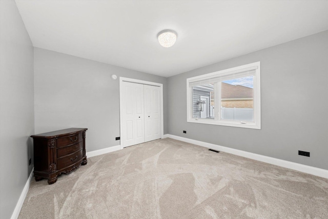 unfurnished bedroom featuring light colored carpet and a closet