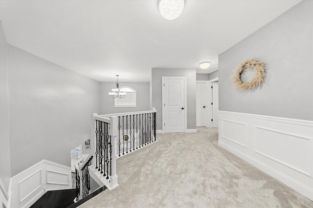 hallway featuring light carpet and a notable chandelier