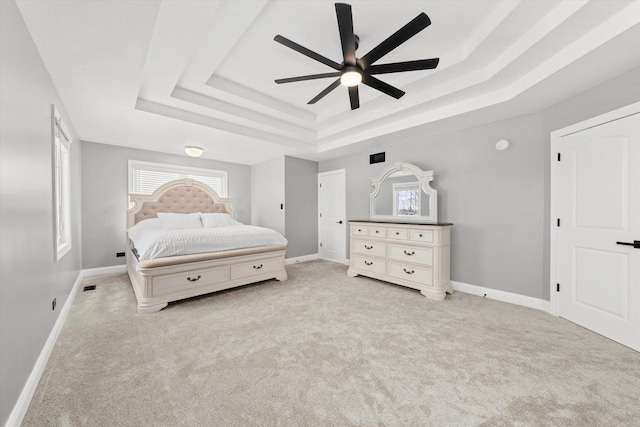 carpeted bedroom featuring ceiling fan and a tray ceiling