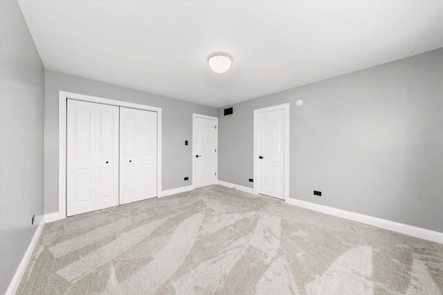 unfurnished bedroom with light colored carpet and a closet