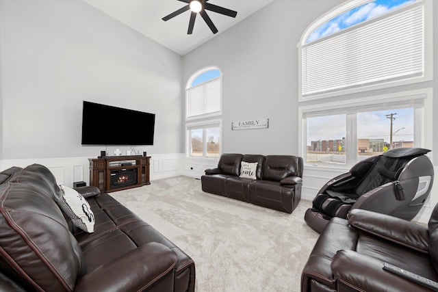 carpeted living room with ceiling fan and high vaulted ceiling