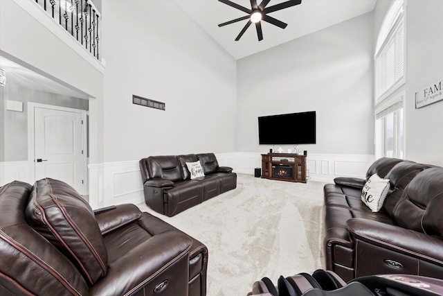 living room featuring carpet flooring, ceiling fan, and a towering ceiling