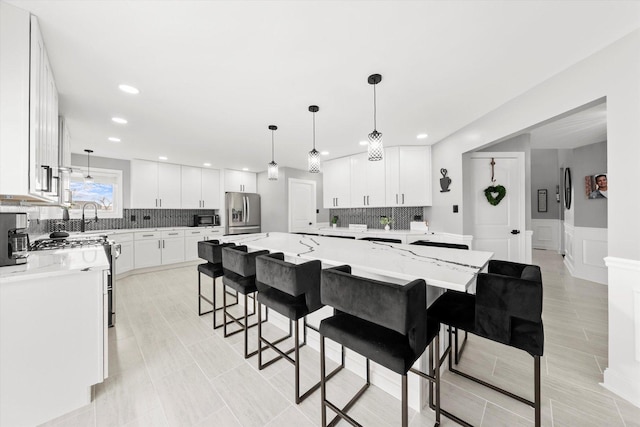 kitchen featuring light stone counters, stainless steel appliances, a large island, and white cabinets